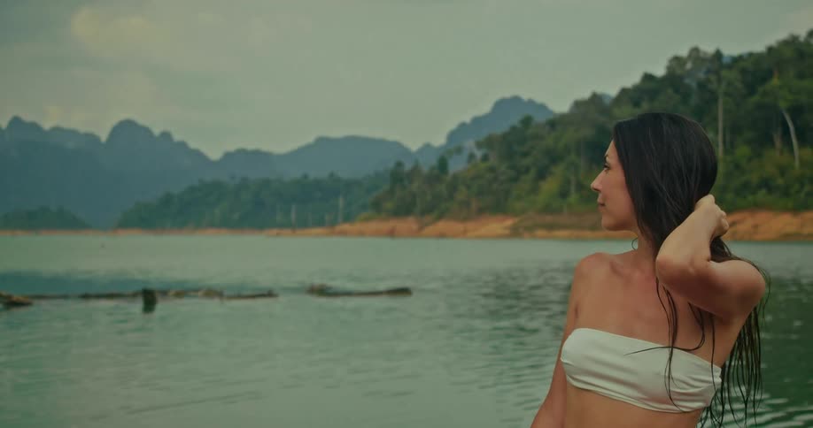 A beautiful woman finds peace and serenity while sitting on a boat, enjoying the stunning views of a tropical mountain lake