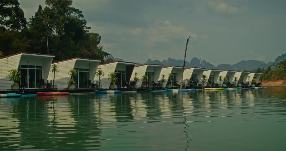 A serene view of modern floating bungalows lining the shore of a tranquil lake in a tropical mountain paradise