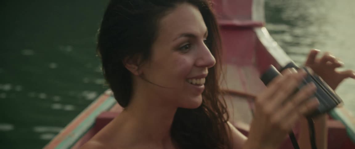 A delighted woman on a boat spots something amazing through her binoculars in slow motion