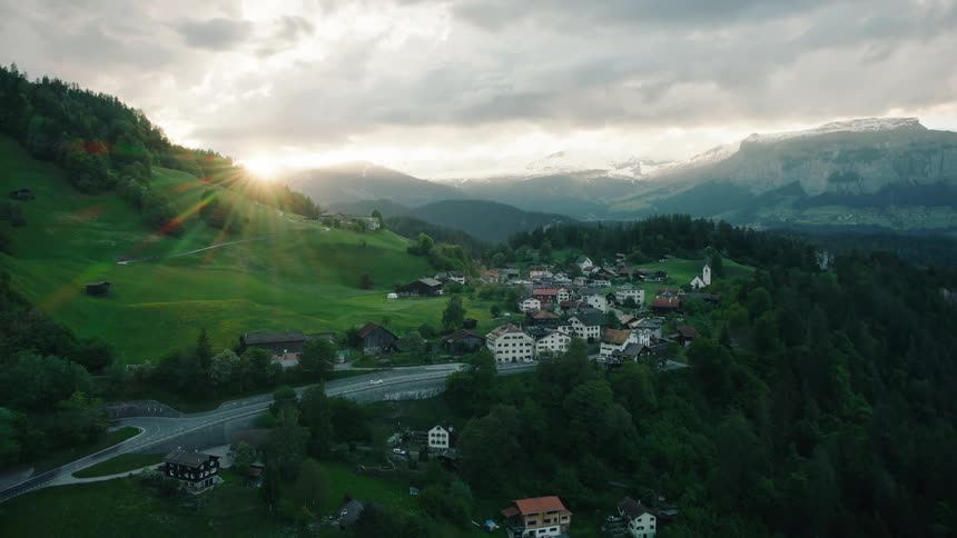A breathtaking aerial view of a Swiss mountain village bathed in the golden light of a setting sun