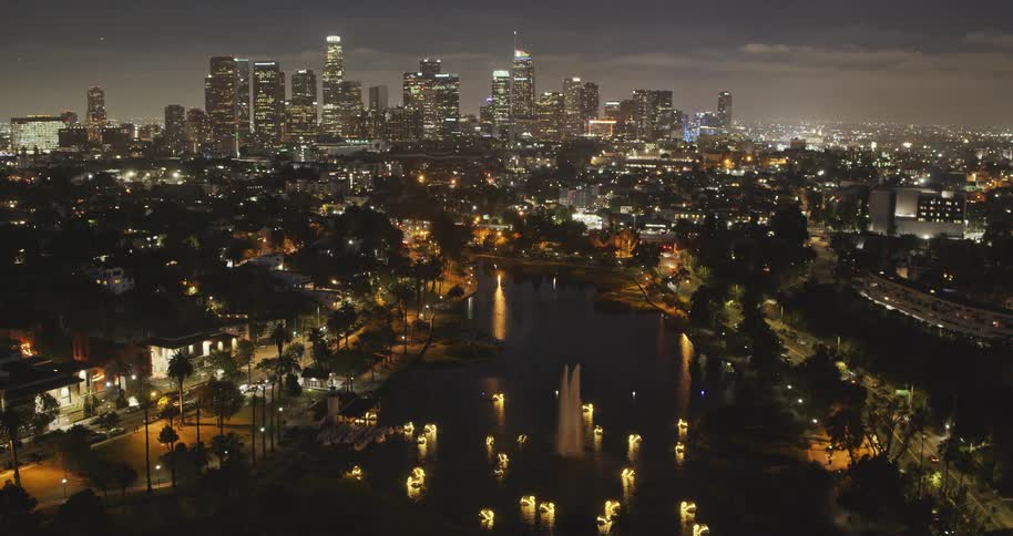 Stunning aerial view of the downtown Los Angeles skyline at night, with the illuminated fountains and swan boats on Echo Park Lake in the foreground