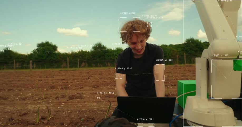 Smiling engineer programs an advanced AI agricultural robot in a field with a futuristic computer vision data overlay
