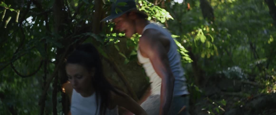A couple has a dramatic and tense argument while exploring a lush green jungle, ending with the woman falling down
