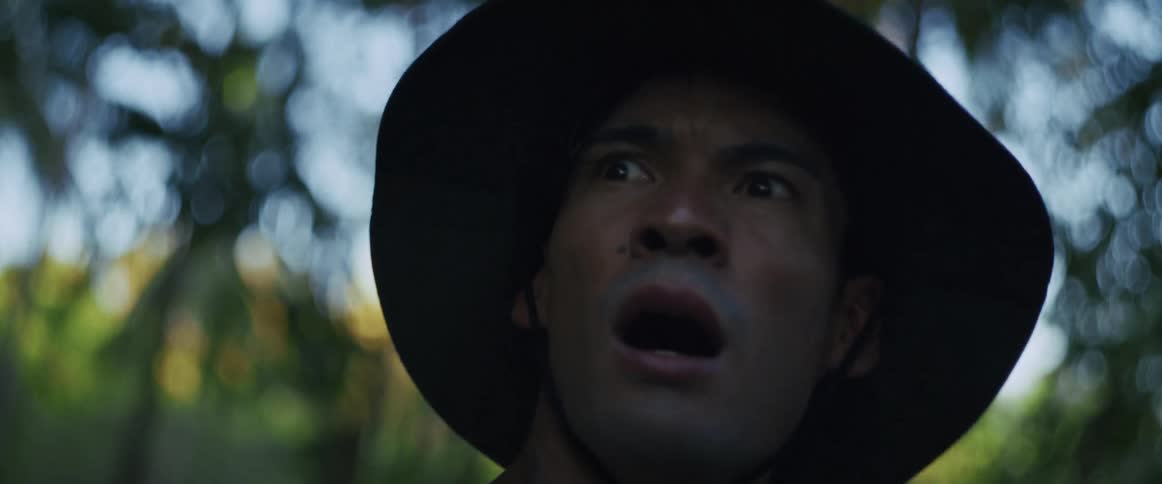 A horrified man in a jungle hat screams in terror after seeing something shocking off-screen