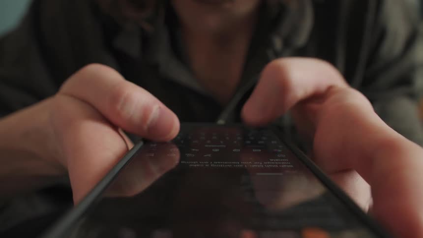 A macro close-up shot captures a person's hands and fingers scrolling and typing on a smartphone screen