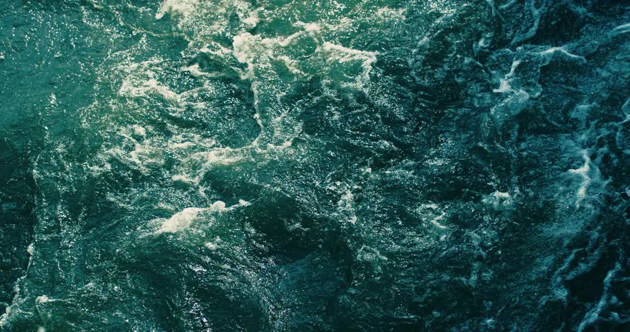 An overhead view of powerful, fast-flowing water creates a hypnotic, turbulent texture in a seamless loop