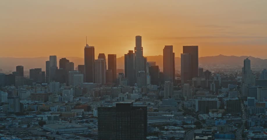 An epic timelapse shows the sun setting behind the towering skyscrapers of the downtown Los Angeles skyline