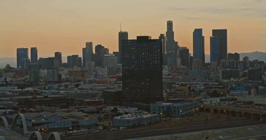 A slow aerial pan reveals the iconic Sixth Street Viaduct and the Downtown Los Angeles skyline at dusk