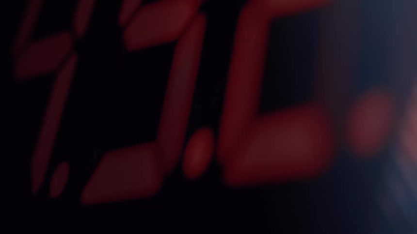 A blurry and shaky extreme close-up shot of a red digital timer counting down on a black background