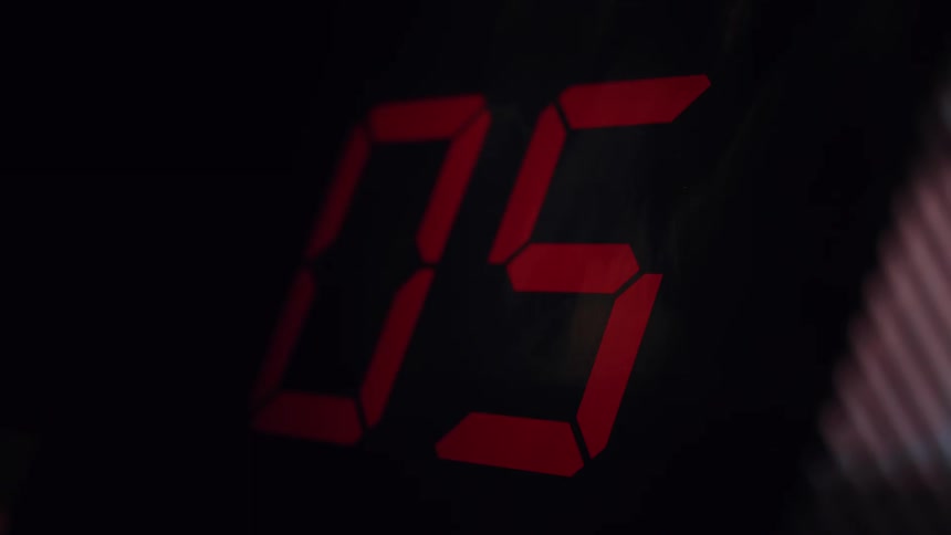 A close-up of a red digital timer counting down from ten to zero on a black background