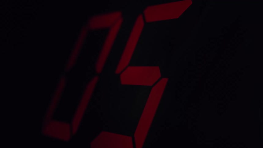 A dramatic close-up of a red digital timer counting down from ten to zero on a black background