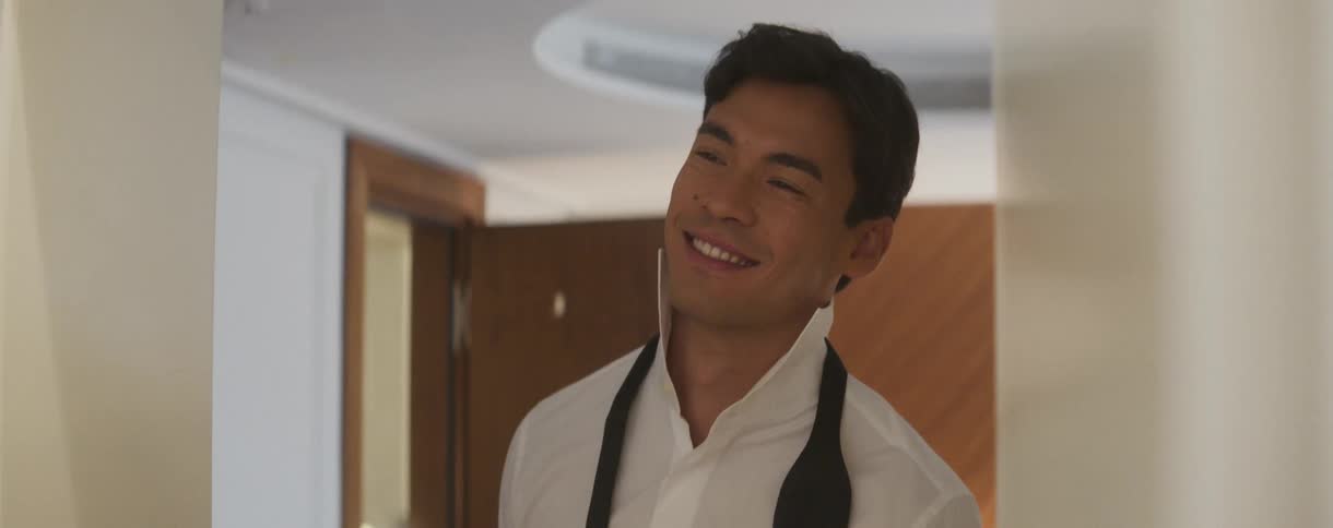 Slow motion close-up of a handsome Asian man smiling with joy and excitement as he gets ready for a formal event