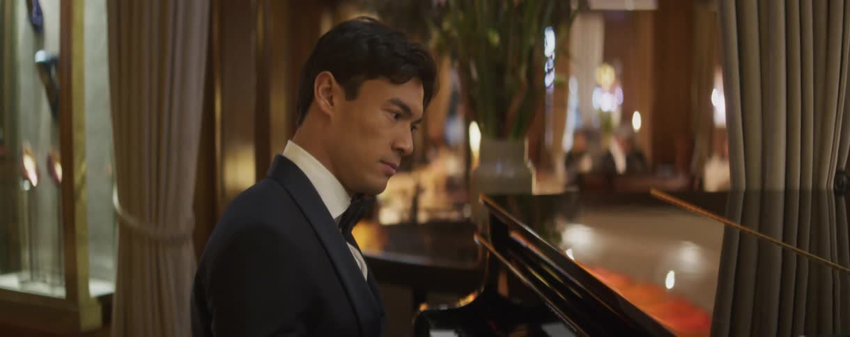 An elegant pianist in a tuxedo gracefully plays a grand piano in a luxurious hotel lounge