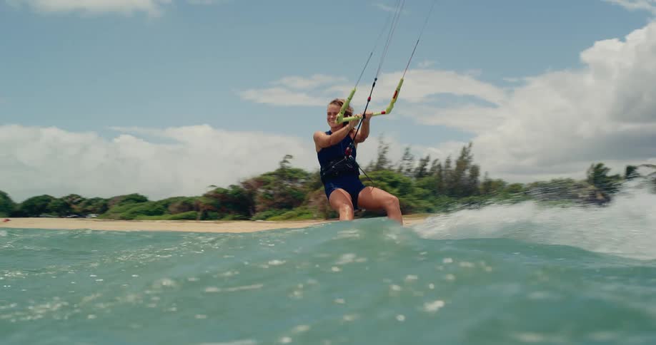 Slow-motion shot of a female kitesurfer gliding towards the camera before the view dips underwater