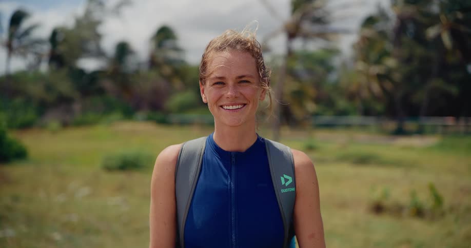Close-up portrait of a happy female athlete smiling at the camera on a windy tropical day