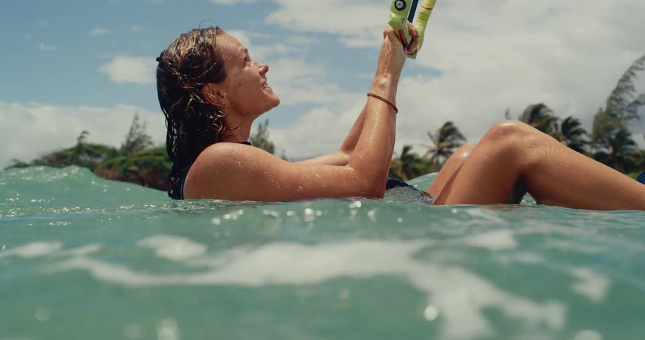 A beautiful young woman kitesurfer smiles and relaxes in the ocean water on a sunny day in slow motion