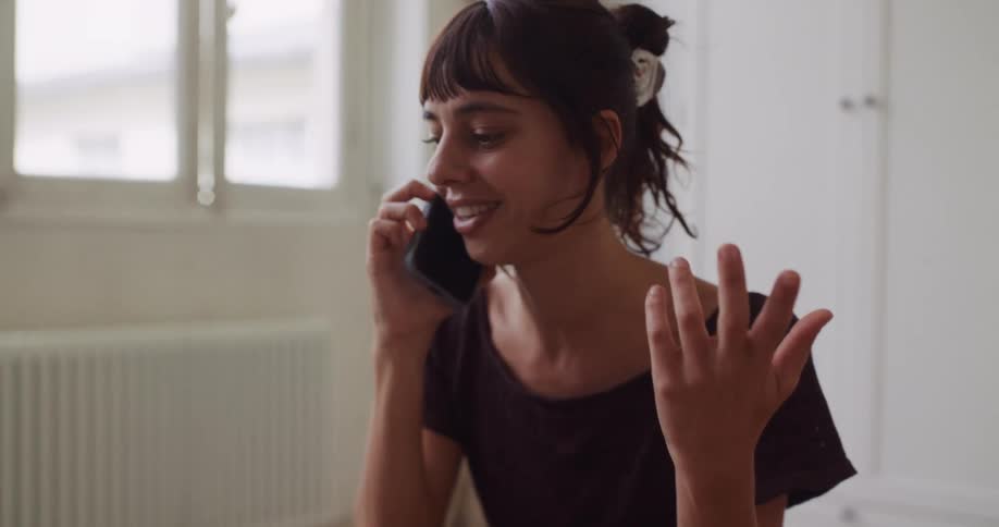 A woman's expression changes from serious to happy while having an animated conversation on her phone in slow motion