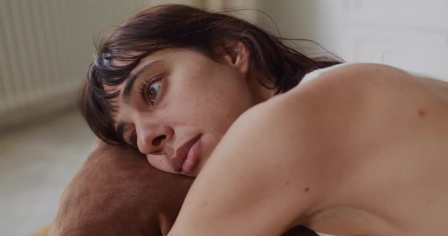 A close-up of a pensive and melancholic young woman resting her head and looking away in thought