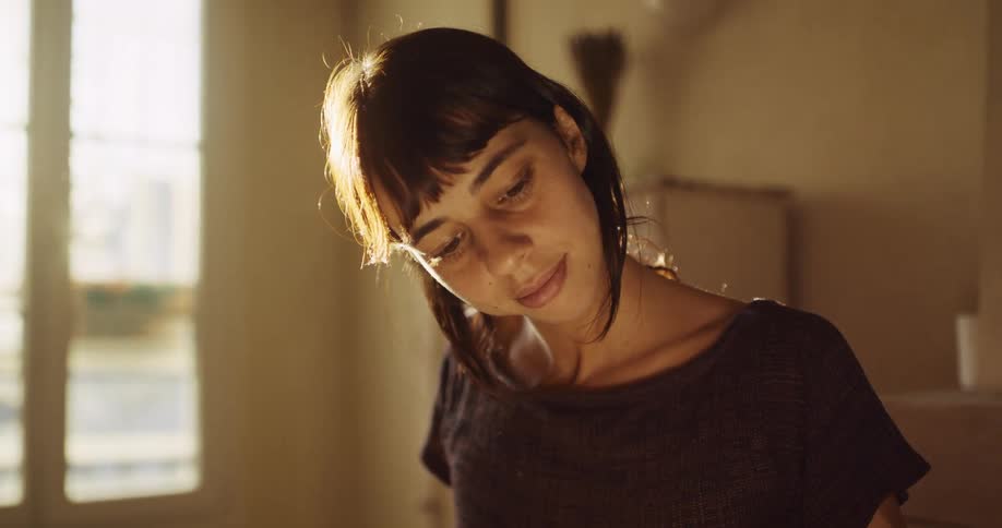 Close-up of a young woman peacefully studying a large book in a warm, naturally lit room