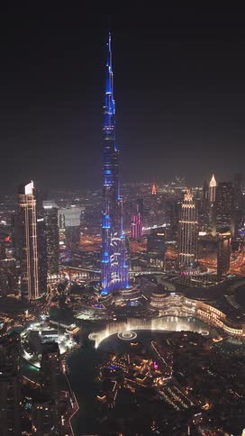 A stunning vertical aerial view of the iconic Burj Khalifa and the Dubai Fountain light and water show illuminating the city at night