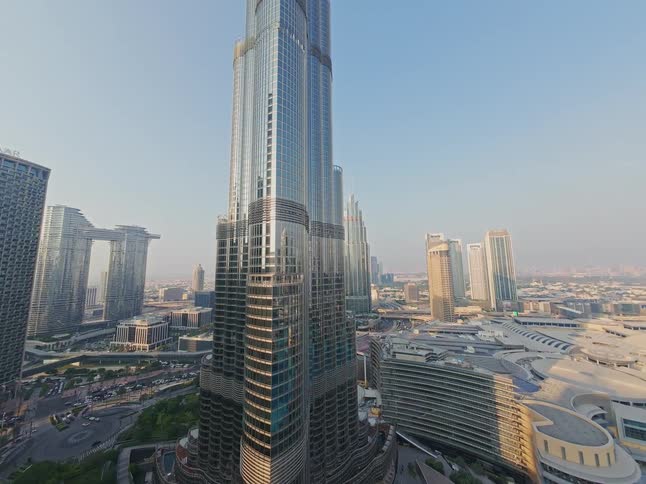 A unique wide-angle aerial view slowly ascends alongside the magnificent Burj Khalifa skyscraper in downtown Dubai