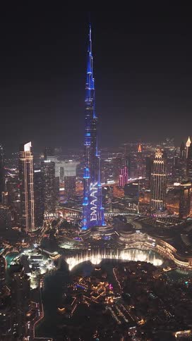 An incredible aerial view of the Burj Khalifa in Dubai at night, illuminated by a stunning blue light show with the city sparkling below