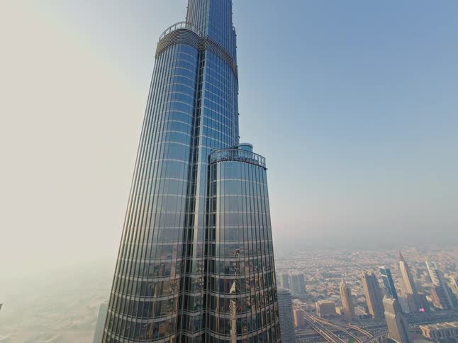 An upward-looking time-lapse view showcases the impressive Burj Khalifa skyscraper towering over the bustling city of Dubai