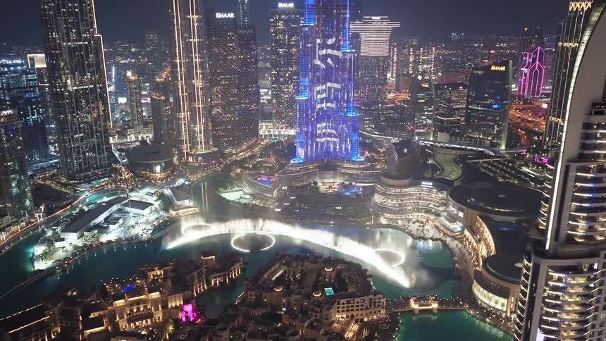 Stunning aerial view of the illuminated Dubai cityscape at night, featuring the Burj Khalifa and the spectacular dancing fountain show