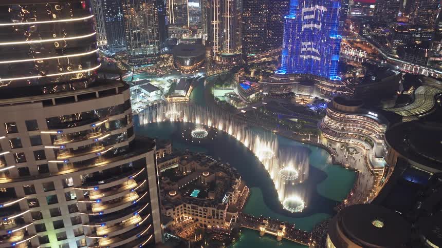 A breathtaking aerial view of the spectacular Dubai Fountain show at night, surrounded by the glowing cityscape and skyscrapers