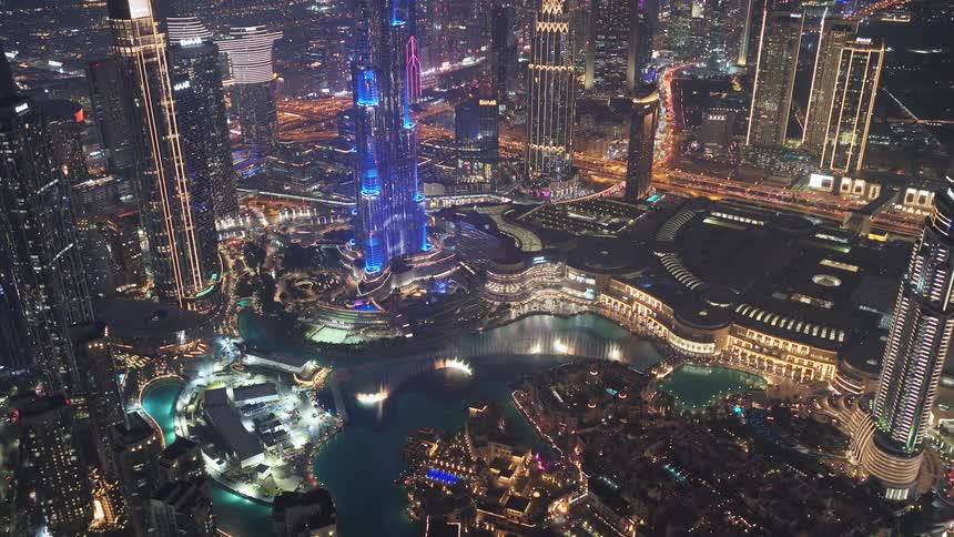 A stunning high-angle view captures the Burj Khalifa and the Dubai Fountain light and water show at night