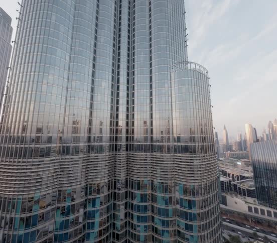 A majestic aerial view slowly ascends the gleaming glass facade of the Burj Khalifa in downtown Dubai