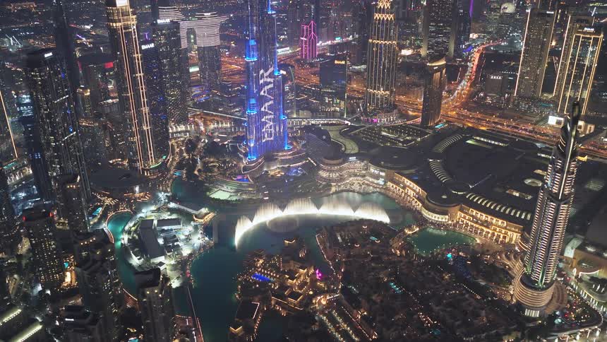 Stunning aerial night view of downtown Dubai, showcasing the spectacular light show on the Burj Khalifa and the mesmerizing Dubai Fountain performance below
