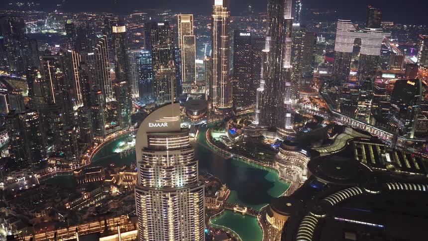 A stunning aerial time-lapse of Downtown Dubai's glittering skyline at night, with traffic flowing below and fountains dancing on the water