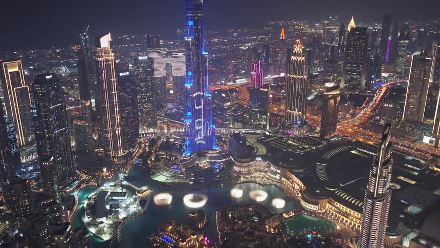 An incredible aerial view reveals the dazzling Dubai skyline at night, with the illuminated Burj Khalifa and the famous fountain show below