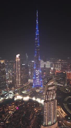 An aerial view of the iconic Burj Khalifa in Dubai at night, illuminated by a captivating blue light show that dazzles against the city skyline
