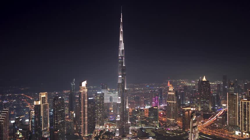 The majestic Burj Khalifa skyscraper dominates the brightly lit Dubai cityscape at night