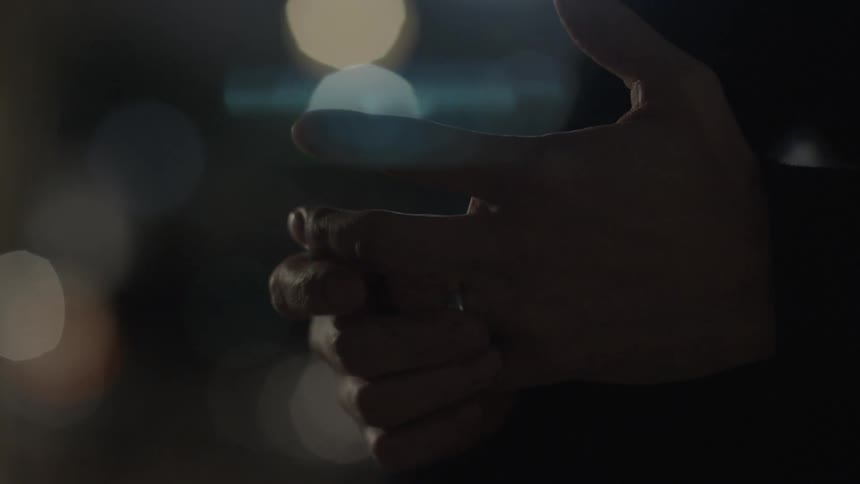 Man spinning his wedding ring on his finger at night