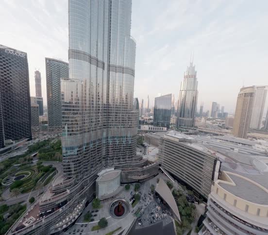 An aerial view slowly ascends alongside the magnificent Burj Khalifa, revealing the sprawling modern cityscape of Dubai