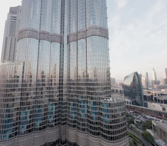 A slow aerial zoom-in reveals the towering, reflective glass facade of the Burj Khalifa in Dubai