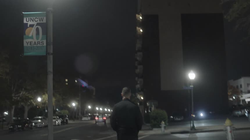 A man is walking in an urban area alone at night