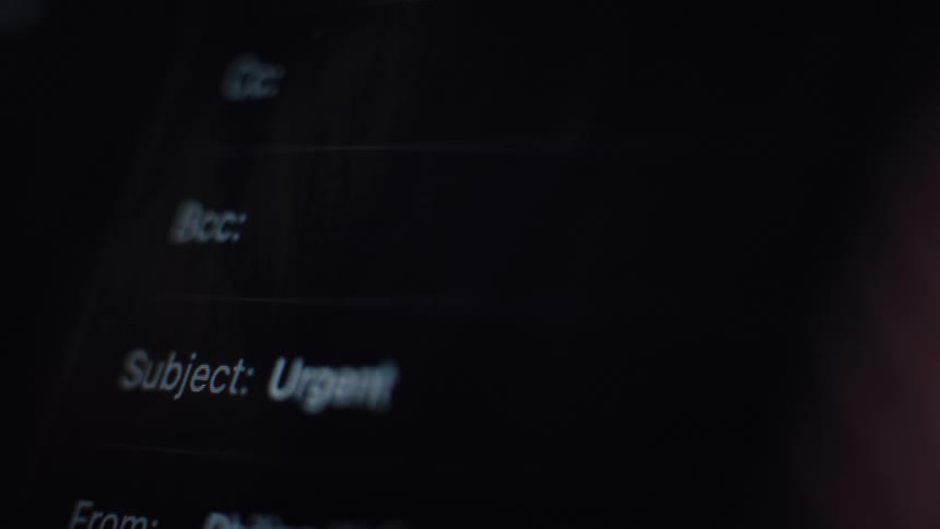 A macro close-up shot of the word 'Urgent' being typed into the subject line of an email on a dark screen