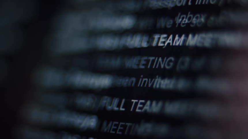 Extreme close-up of a computer screen showing a rapidly scrolling email inbox with shallow depth of field