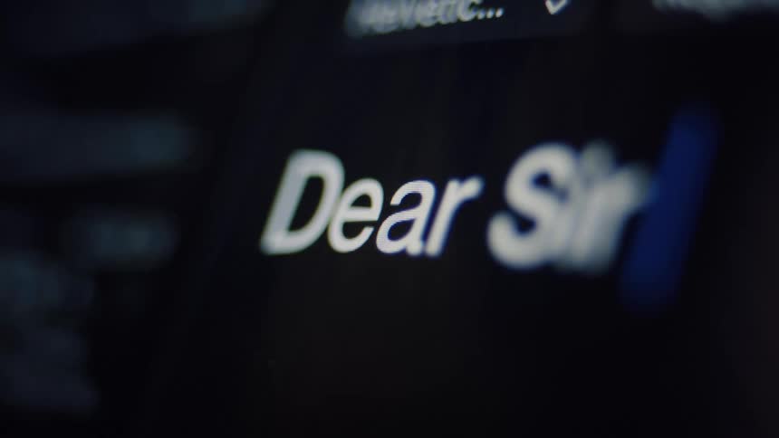Typing the formal salutation 'Dear Sir' in white text on a dark computer screen