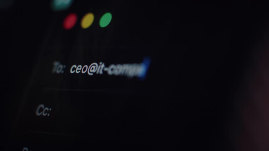 A person types an email address to the CEO of an IT company on a computer screen in a dark room