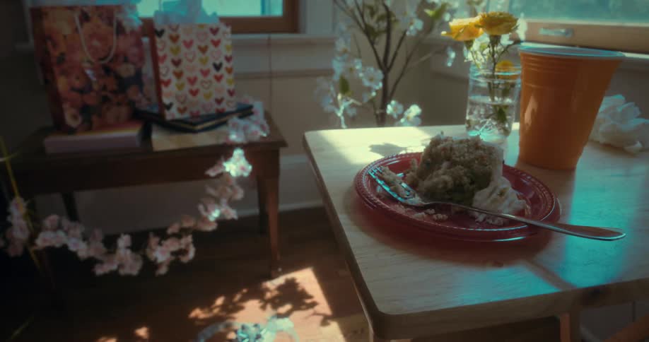 The quiet aftermath of a party with a slice of cake left on the table as sunlight streams through the window