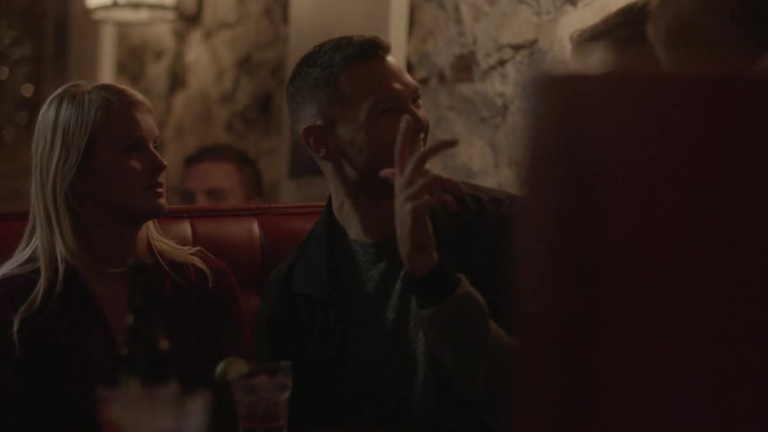 A man laughs and talks with his friends while in a bar