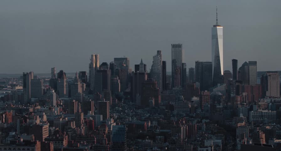 Static aerial view of the Lower Manhattan skyline and Freedom Tower under a muted evening sky