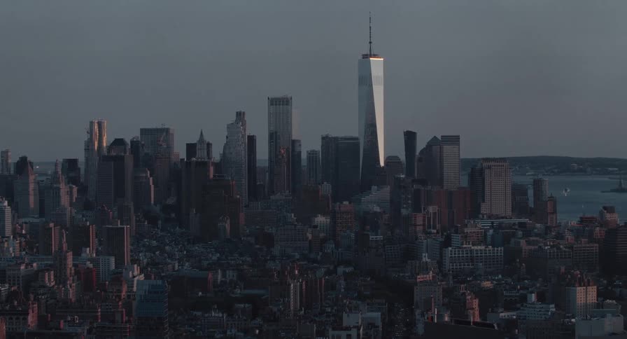 A moody static shot of the downtown Manhattan skyline at dusk as the sun sets on the city