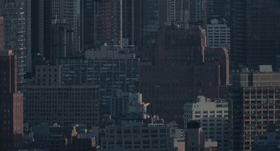 A static telephoto shot captures the dense architecture of a major city in the cool morning light