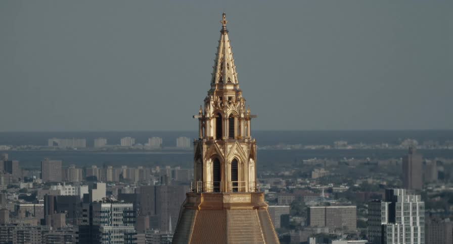 A detailed static shot of the golden gilded roof of the New York Life Building overlooking the city skyline